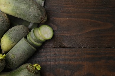 Photo of Green daikon radishes on wooden table, flat lay. Space for text
