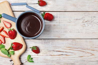 Chocolate fondue with strawberries and marshmallow on wooden table