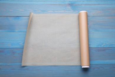 Roll of baking paper on light blue wooden table, top view