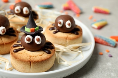 Photo of Delicious biscuits with chocolate spiders on light grey table, closeup. Halloween celebration