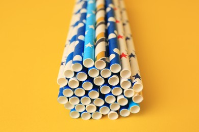 Photo of Colorful paper drinking straws on yellow background, closeup