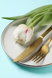Photo of Stylish table setting with cutlery and tulips on light blue background