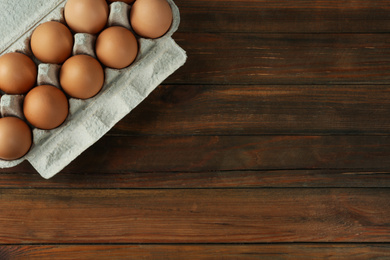 Raw chicken eggs on wooden table, top view. Space for text