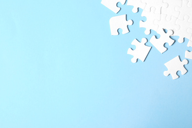 Photo of Blank white puzzle pieces on light blue background, flat lay. Space for text