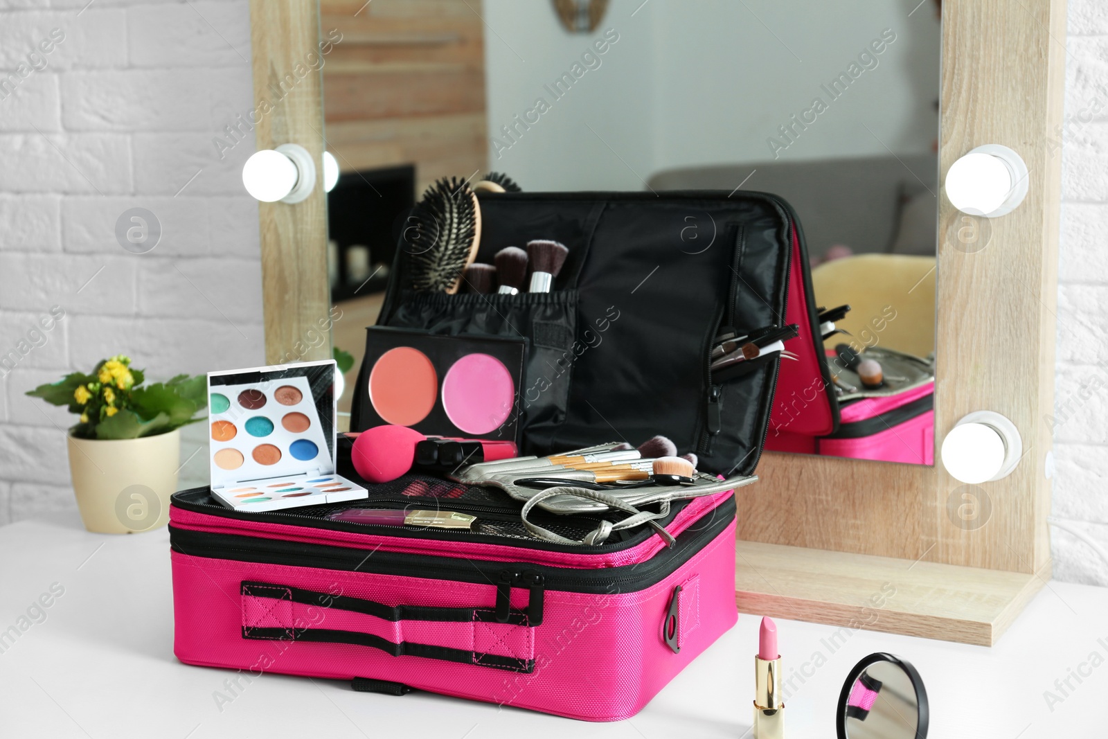 Photo of Beautician case with professional makeup products and tools on dressing table