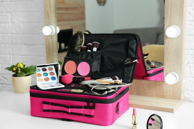 Beautician case with professional makeup products and tools on dressing table