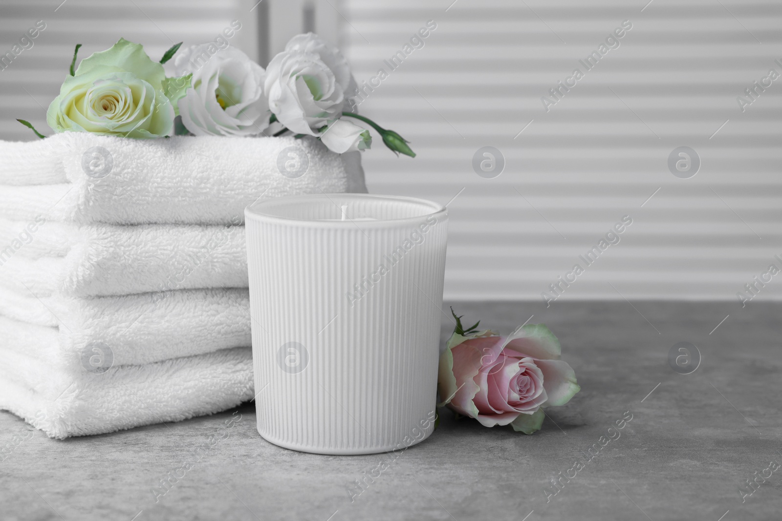 Photo of Towels, scented candle and flowers on grey table indoors