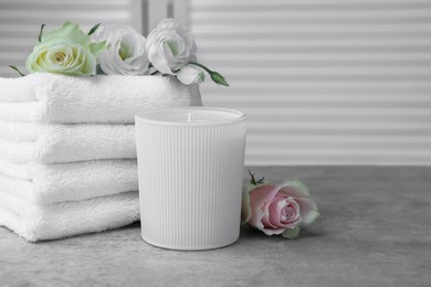 Photo of Towels, scented candle and flowers on grey table indoors