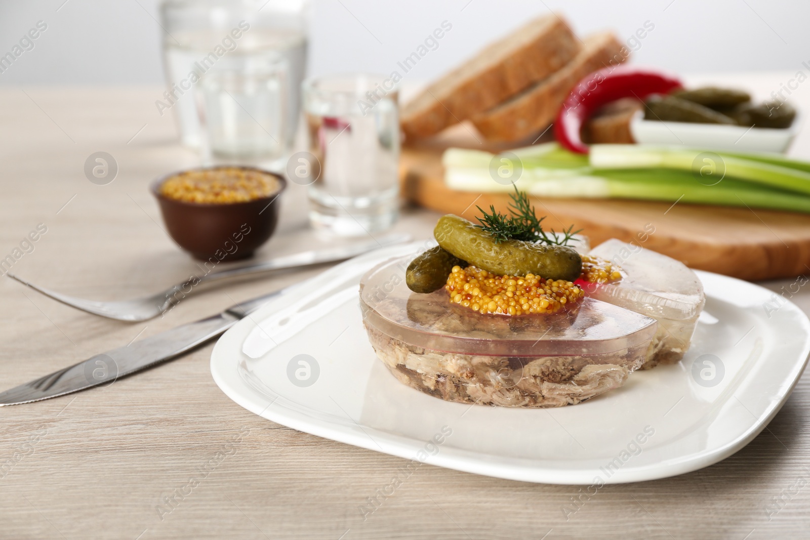 Photo of Delicious aspic with meat and vegetables served on light wooden table