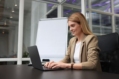 Woman working on laptop at black desk in office