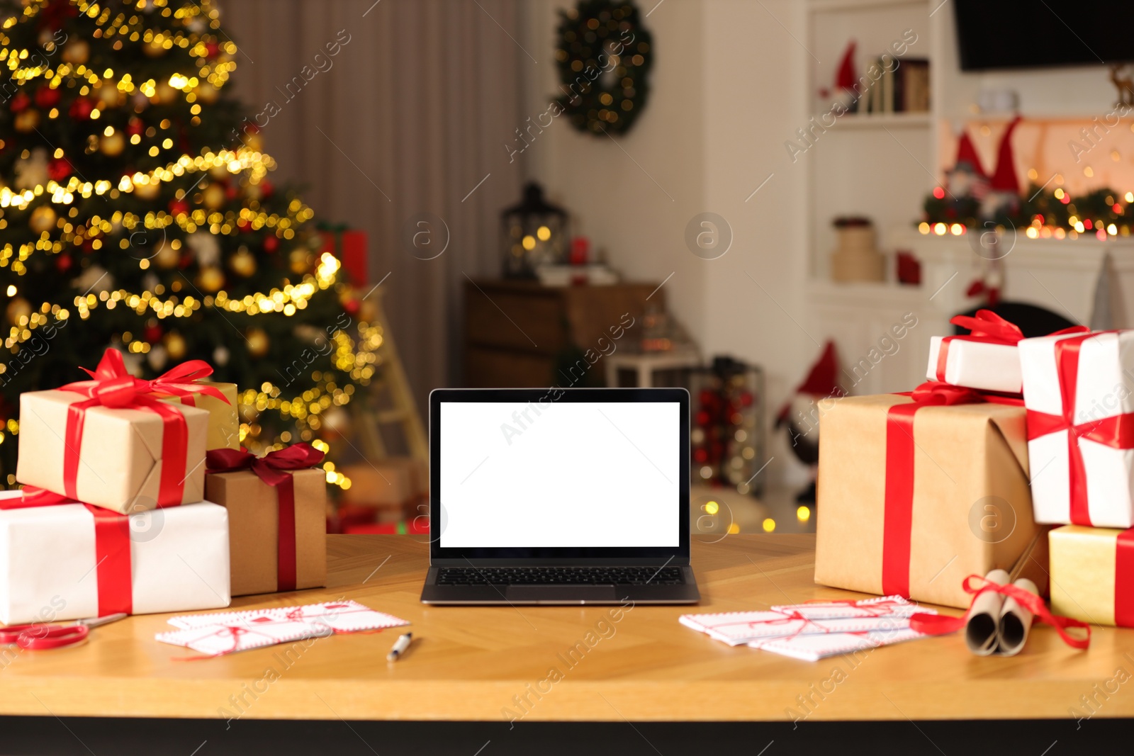 Photo of Laptop with blank screen, Christmas gifts and letters on table at home