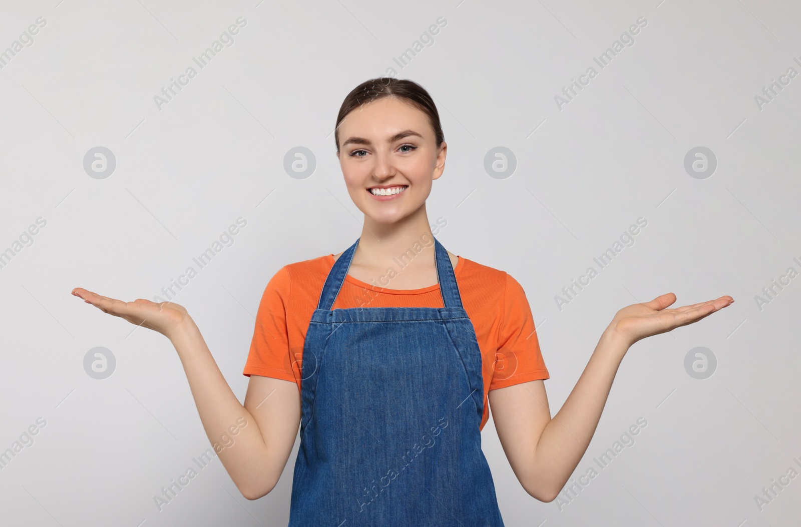 Photo of Beautiful young woman in clean denim apron on light grey background