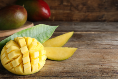 Photo of Cut fresh ripe mango on wooden table. Space for text