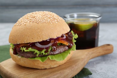 Photo of Board with delicious cheeseburger on table, closeup