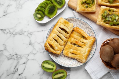 Photo of Fresh tasty puff pastry with kiwi on white marble table, flat lay. Space for text