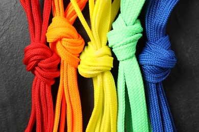 Photo of Colorful shoelaces on black background, flat lay