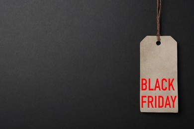 Image of LIght grey tag with phrase BLACK FRIDAY on dark background, top view. Space for text