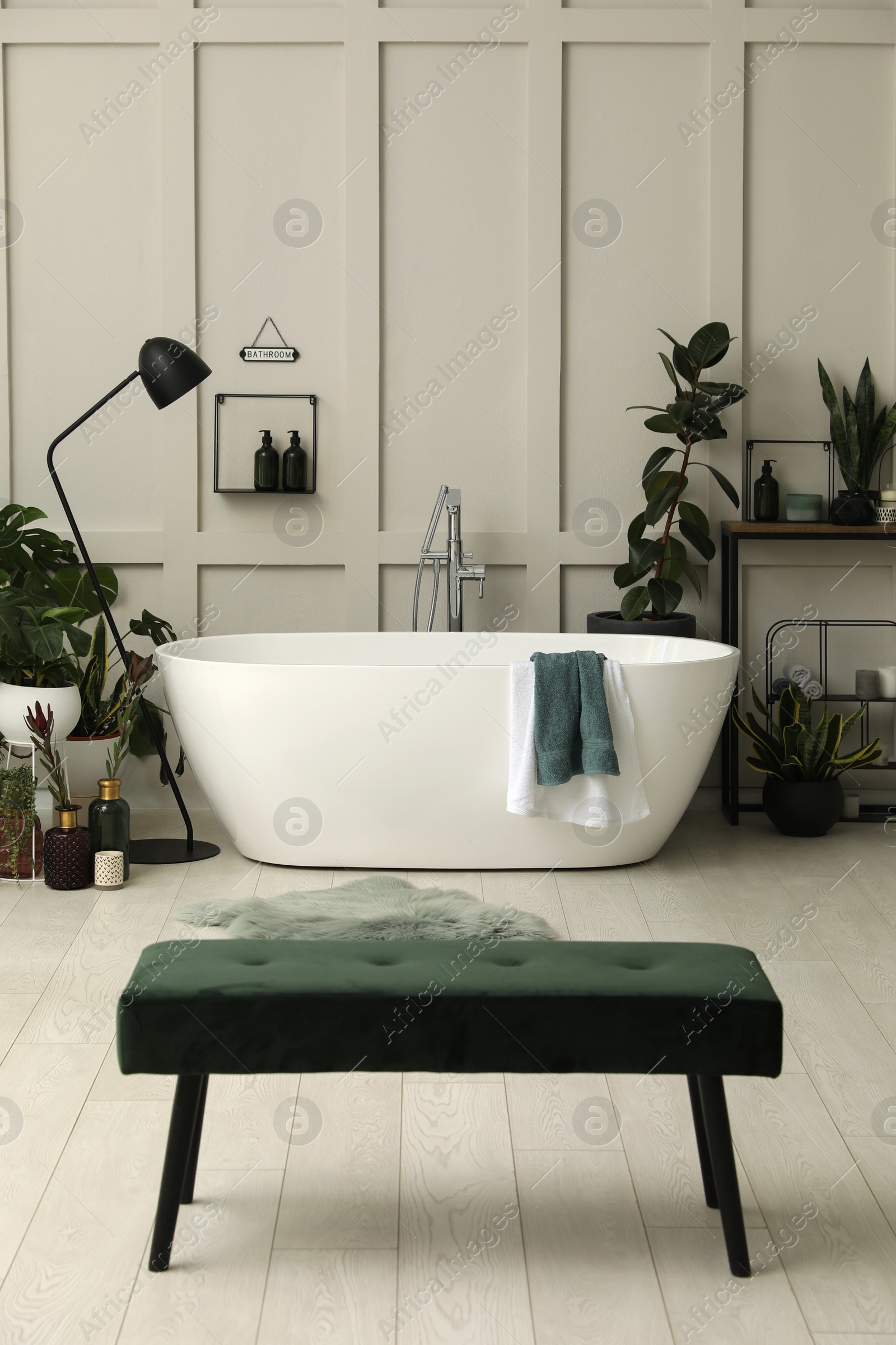 Photo of Stylish bathroom interior with modern tub and beautiful houseplants. Home design