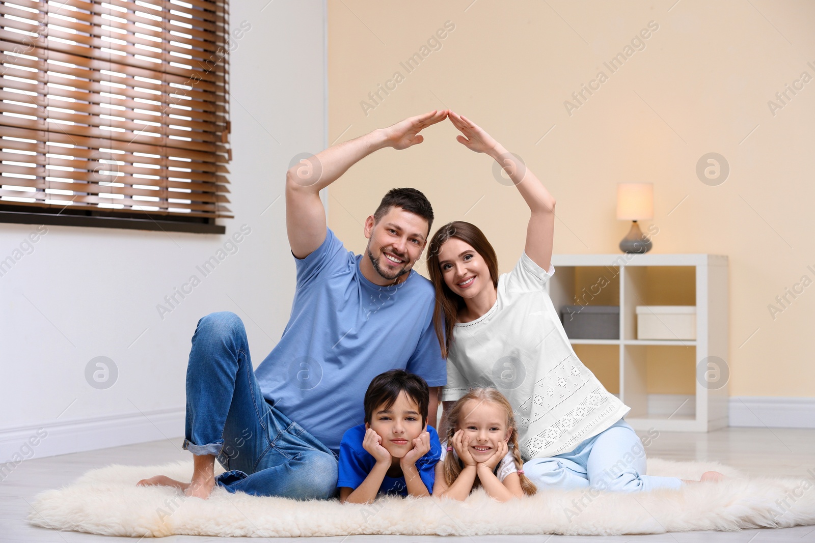 Photo of Happy family forming house roof with their hands at home. Insurance concept