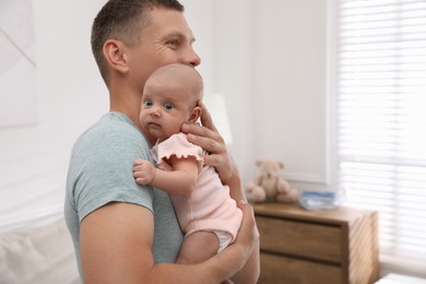 Happy father holding his cute little baby at home, space for text