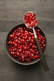 Tasty ripe pomegranate grains on dark wooden table, top view