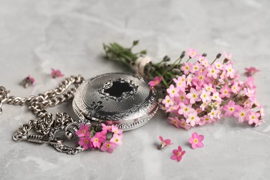 Photo of Beautiful Forget-me-not flowers and pocket watch on grey table