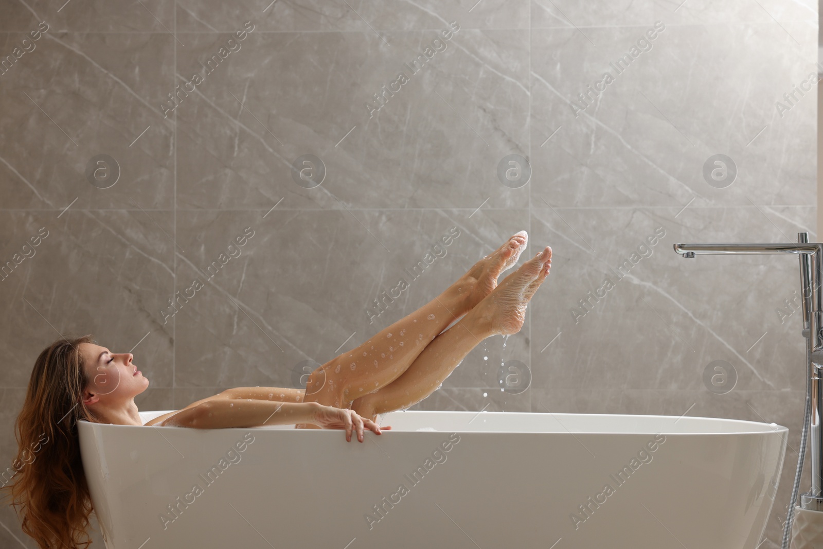 Photo of Beautiful woman taking bath with foam indoors