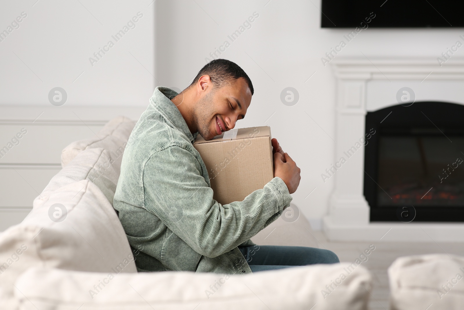 Photo of Happy young man with parcel at home. Internet shopping