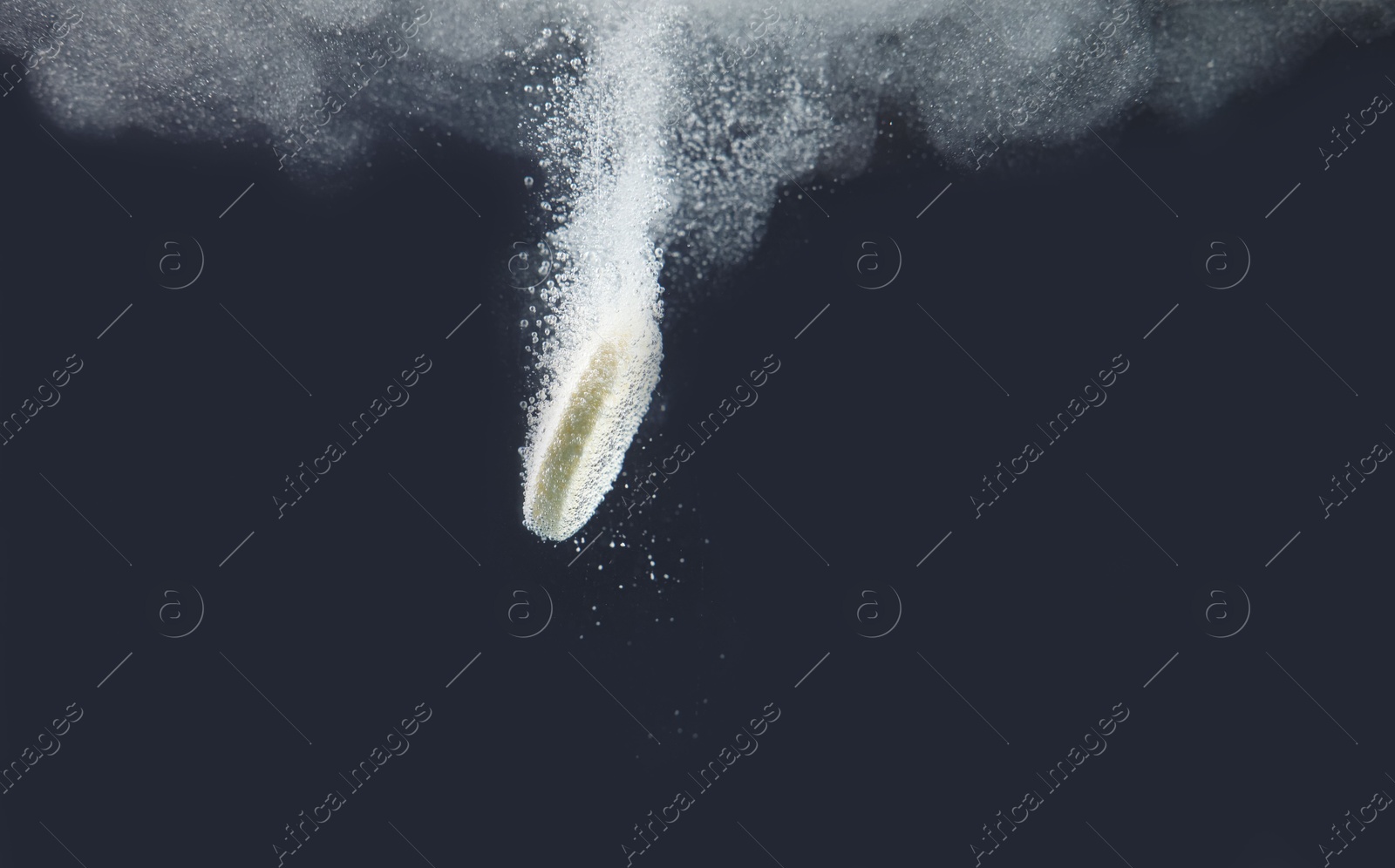 Photo of Effervescent pill dissolving in water on dark background, closeup