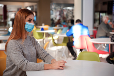 Photo of Woman with medical mask in cafe. Virus protection