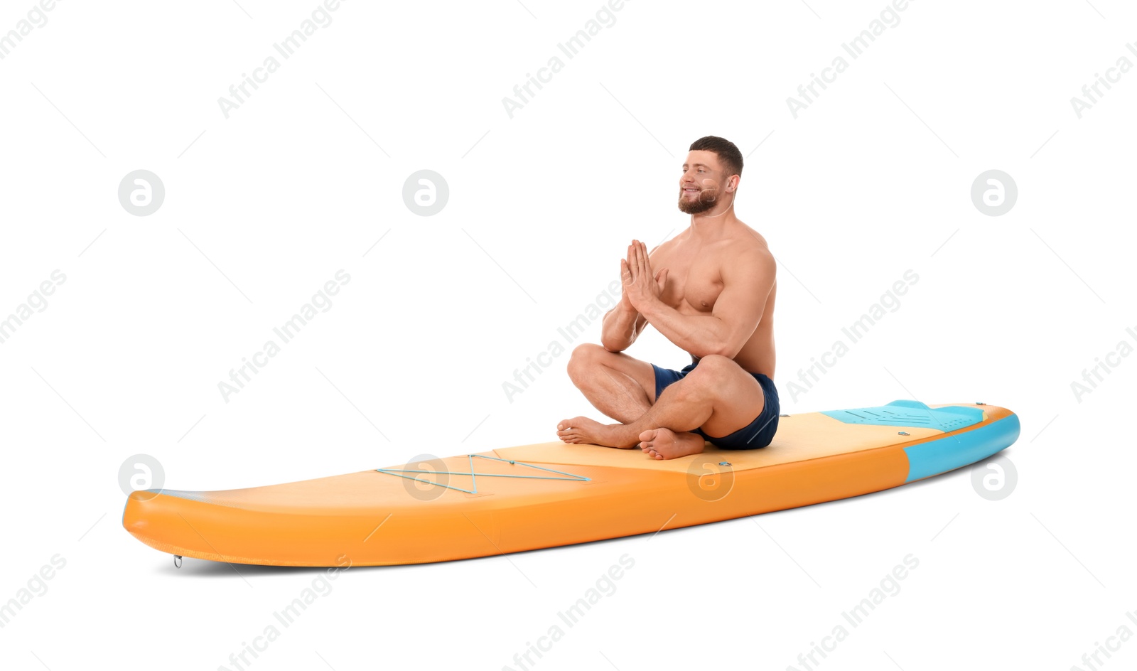 Photo of Happy man practicing yoga on orange SUP board against white background