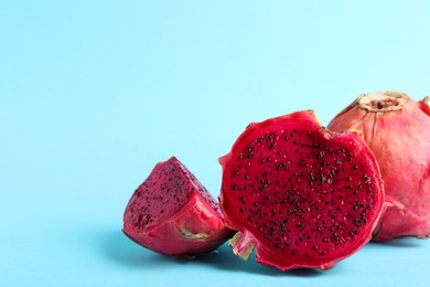 Photo of Delicious cut and whole red pitahaya fruits on light blue background. Space for text