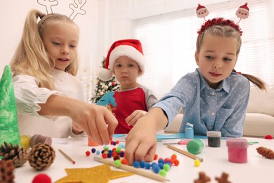 Photo of Cute little children making Christmas crafts at table in decorated room