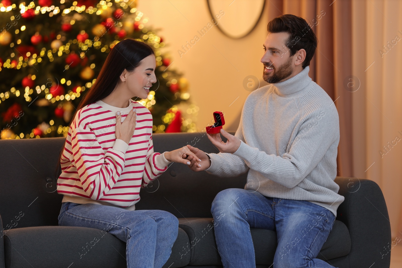 Photo of Man with engagement ring making proposal to his girlfriend at home on Christmas