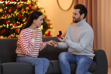 Photo of Man with engagement ring making proposal to his girlfriend at home on Christmas