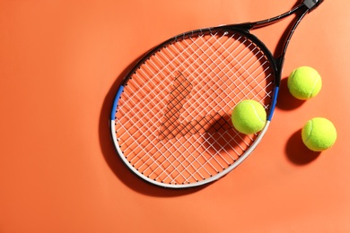 Photo of Tennis racket and balls on orange background, flat lay. Sports equipment