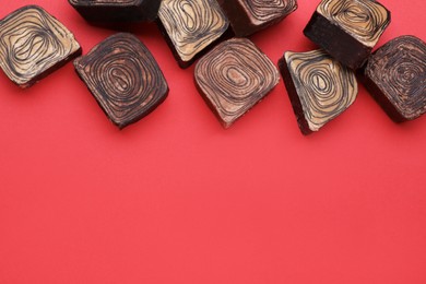 Different tasty chocolate candies on red background, flat lay. Space for text