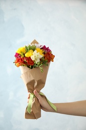 Photo of Woman holding bouquet of beautiful spring freesia flowers on color background