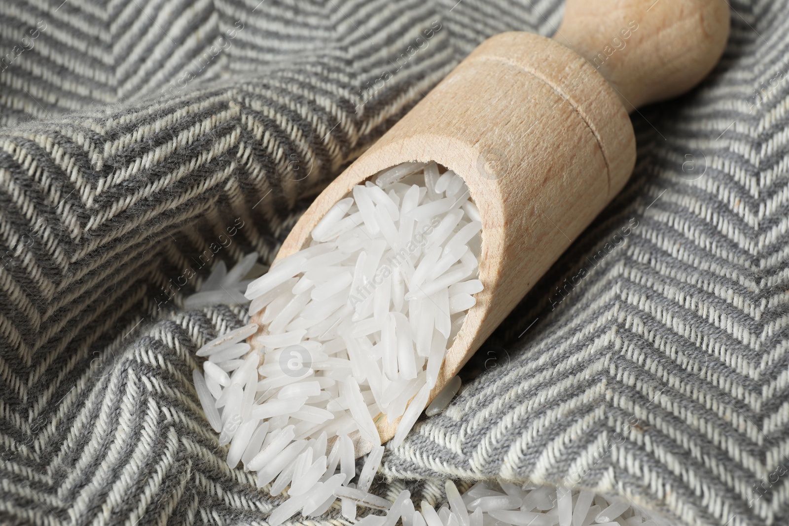 Photo of Raw basmati rice in scoop on fabric, closeup