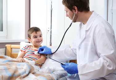 Photo of Doctor examining little child with stethoscope in hospital