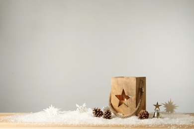 Composition with wooden Christmas lantern on table against light grey background, space for text