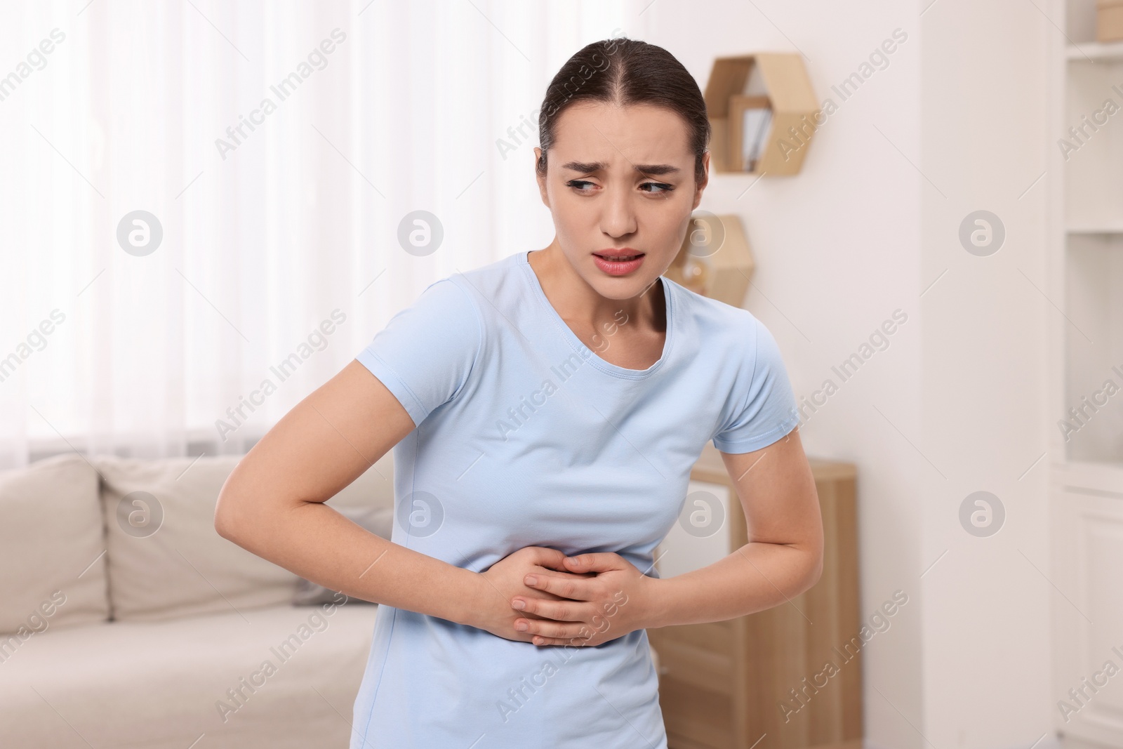 Photo of Woman suffering from abdominal pain at home. Unhealthy stomach