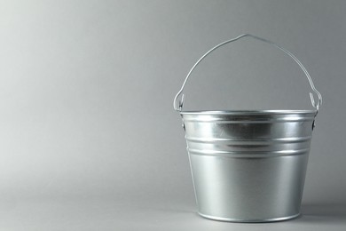 Photo of One shiny metal bucket on light grey background. Space for text