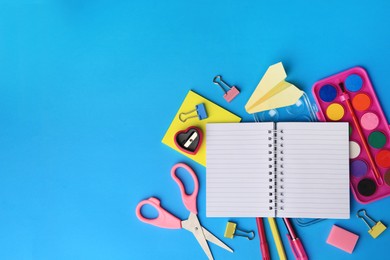 Photo of Flat lay composition with blank notebook and other school stationery on light blue background, space for text. Back to school