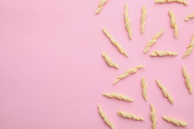 Photo of Uncooked trofie pasta on pink background, flat lay. Space for text
