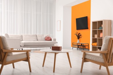 Photo of Comfortable furniture and sofa near orange wall in room. Interior design
