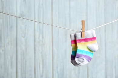 Photo of Pair of socks on laundry line against wooden background, space for text. Baby accessories