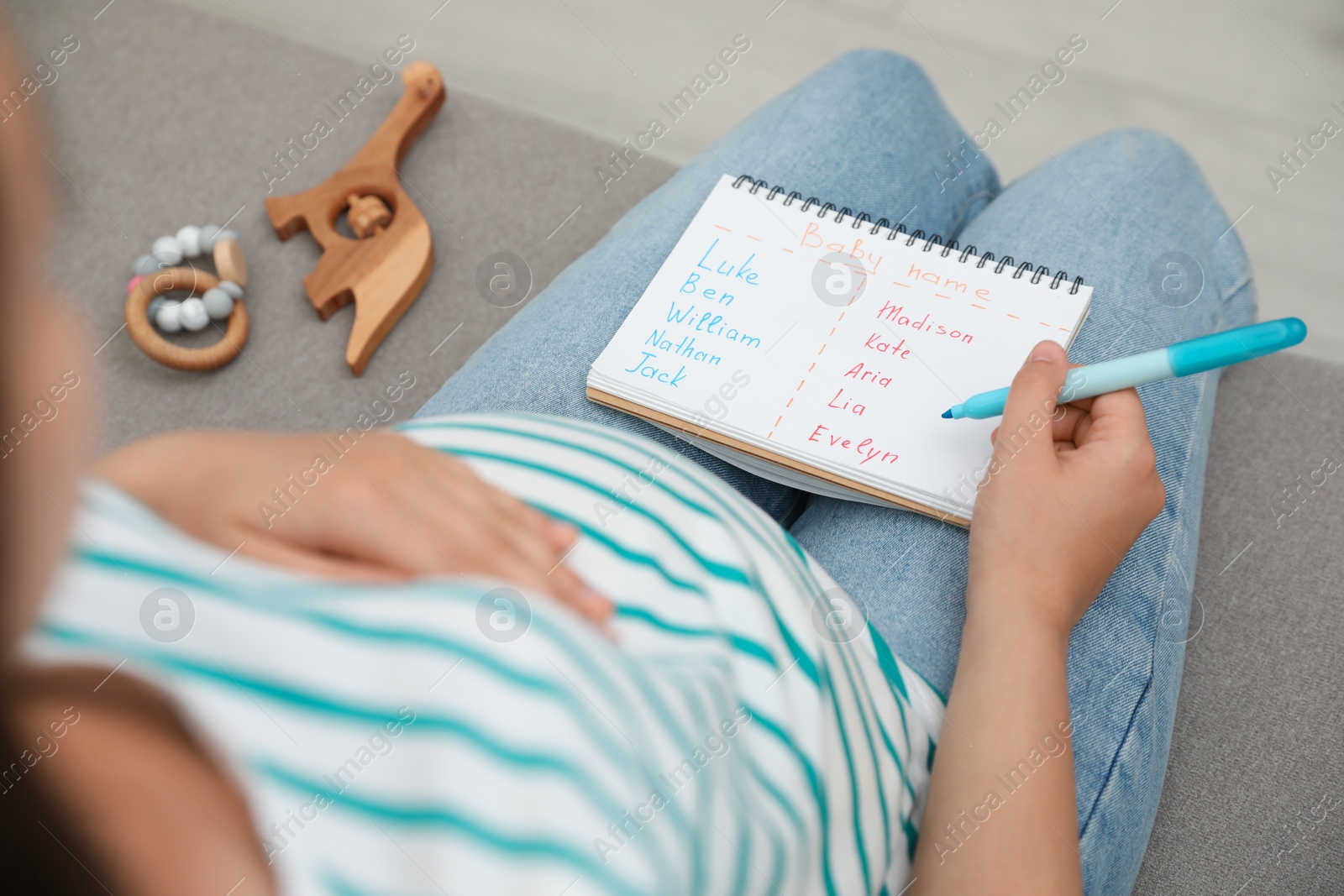 Photo of Pregnant woman with baby names list sitting on sofa, closeup