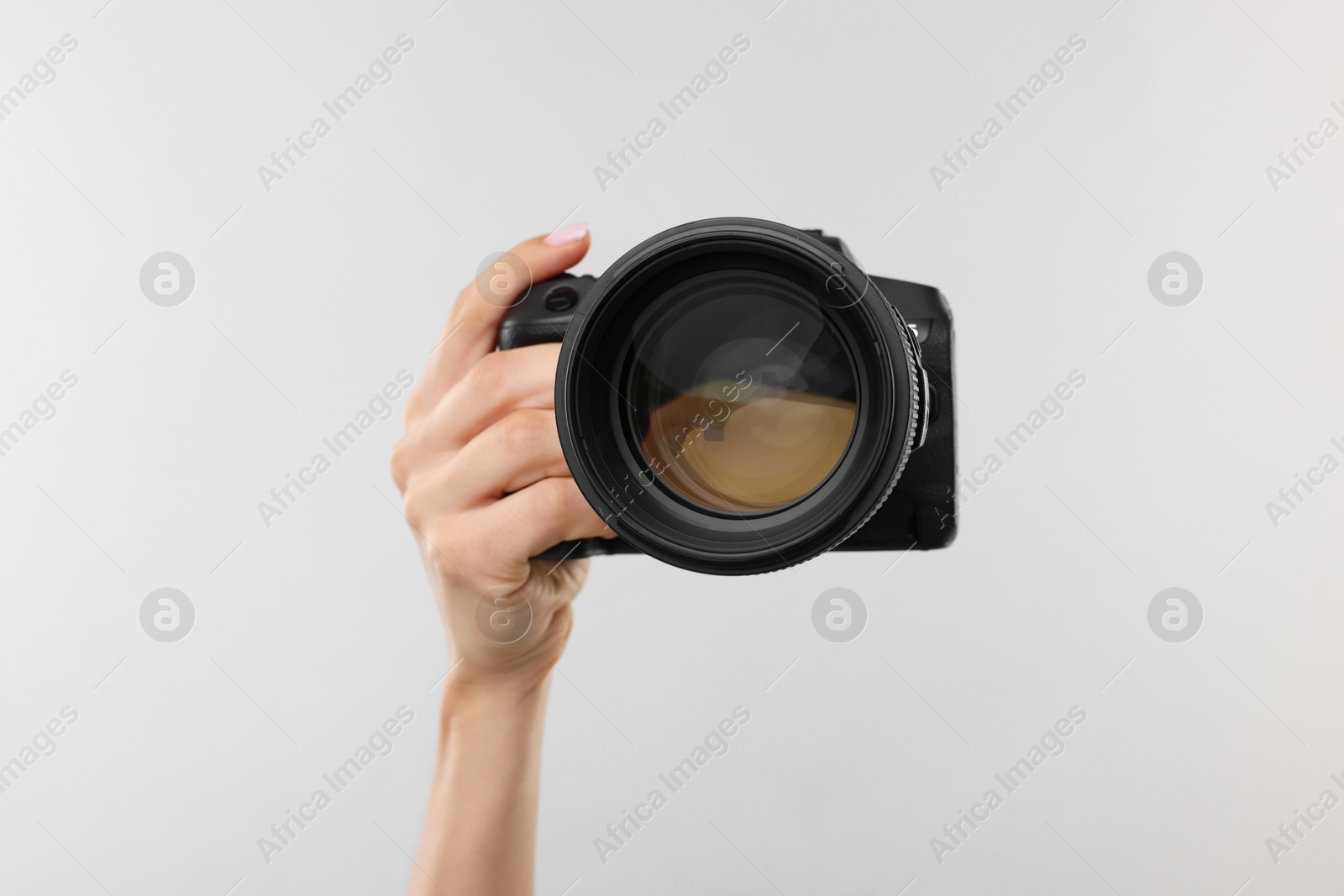 Photo of Photographer with camera on light grey background, closeup