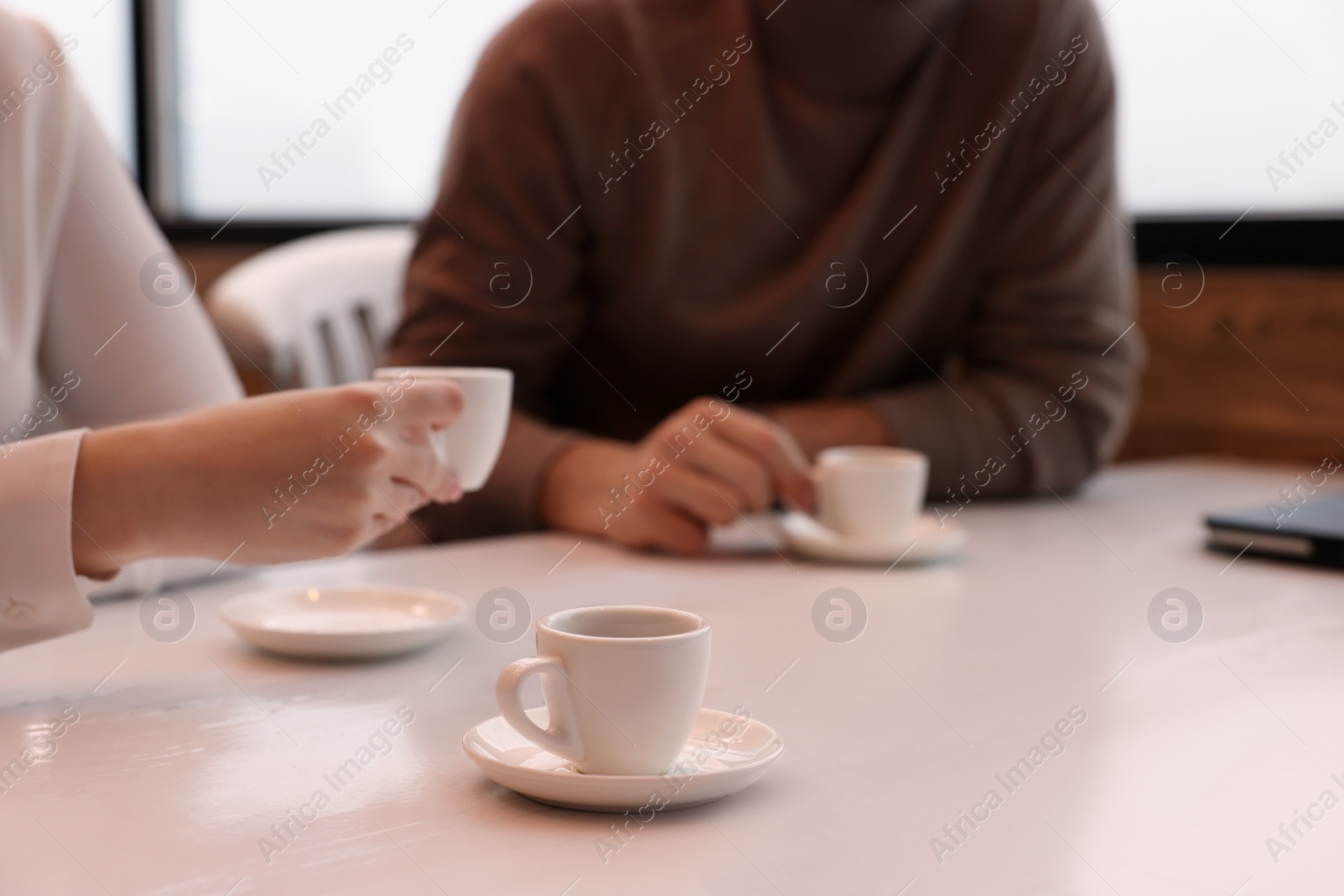 Photo of Coworkers enjoying coffee during break in cafe, focus on cup. Space for text